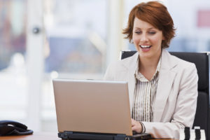 Happy young businesswoman working on laptop